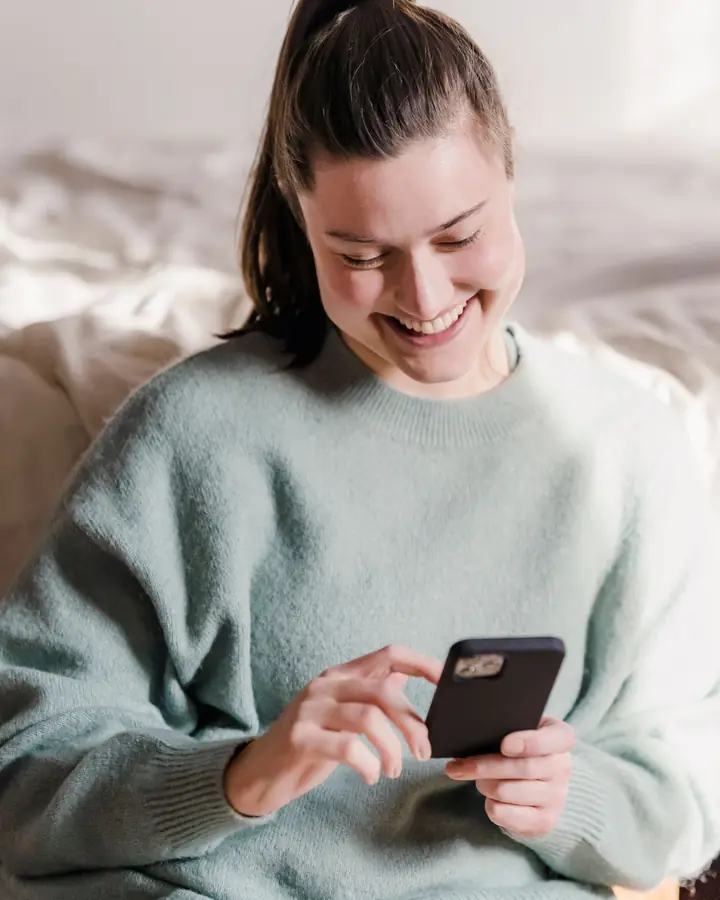 A customer smiling at a fast reply on her phone